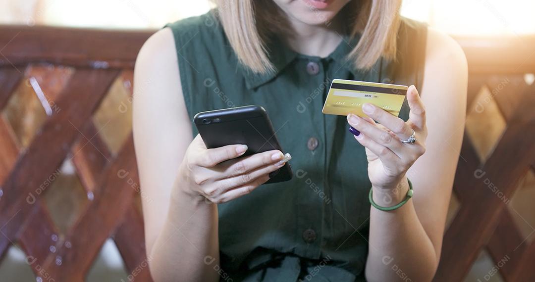 mulher asiática usando smartphone e cartão de crédito compras online