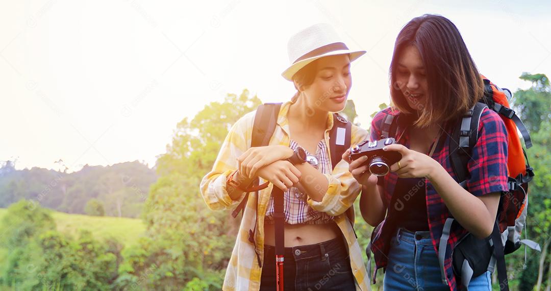Grupo asiático de jovens Caminhando com mochilas de amigos caminhando juntos e olhando o mapa e tirando a câmera fotográfica pela estrada e parecendo feliz, Relaxe o tempo em viagens de conceito de férias