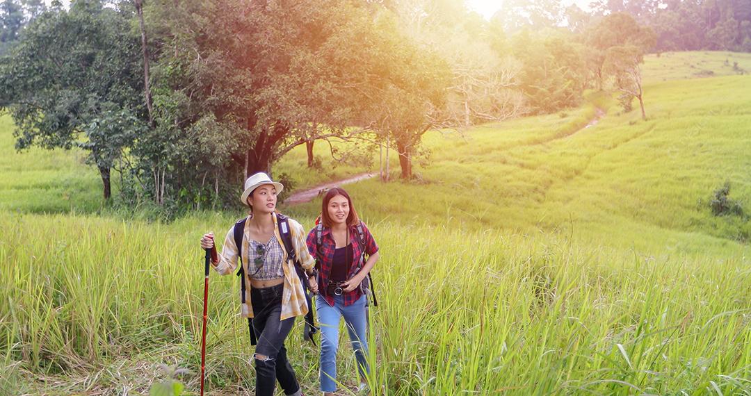 Grupo asiático de jovens Caminhando com mochilas de amigos caminhando juntos e olhando o mapa e tirando a câmera fotográfica pela estrada e parecendo feliz, Relaxe o tempo em viagens de conceito de férias