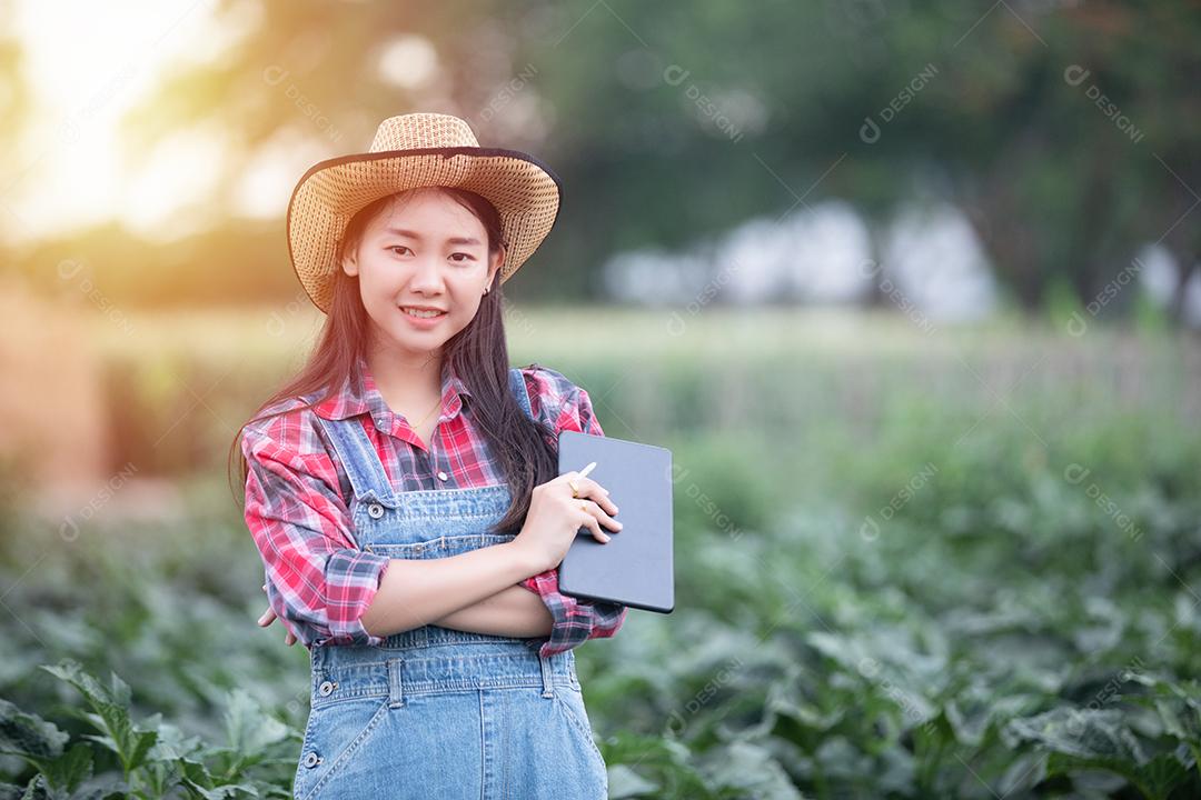Mulheres asiáticas agrônomas e agricultoras usando tecnologia para inspecionar no campo de vegetais agrícolas e orgânicos