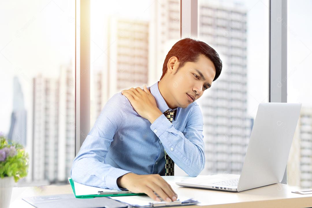 Homem de negócios asiático com dor nas costas pecam em um escritório e levam a sério o trabalho feito até a dor de cabeça em trabalhar duro