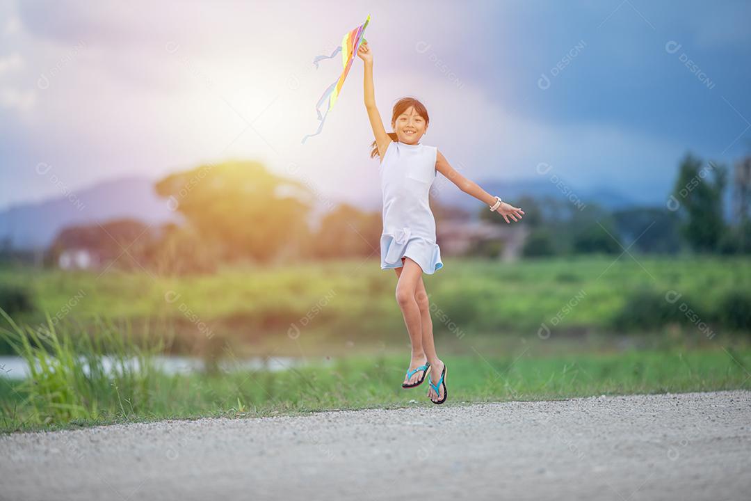 Menina asiática e pai com uma pipa correndo e feliz no prado no verão na natureza