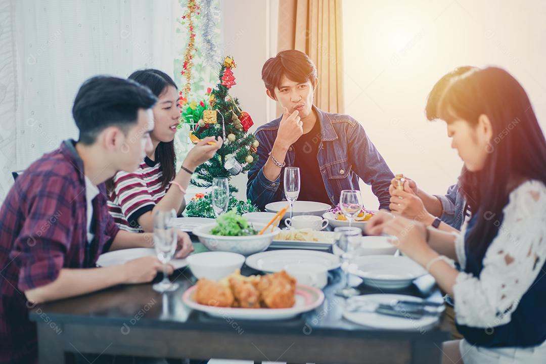 Jantar com o grupo asiático de melhores amigos desfrutando de bebidas à noite enquanto estão sentados à mesa de jantar na cozinha juntos