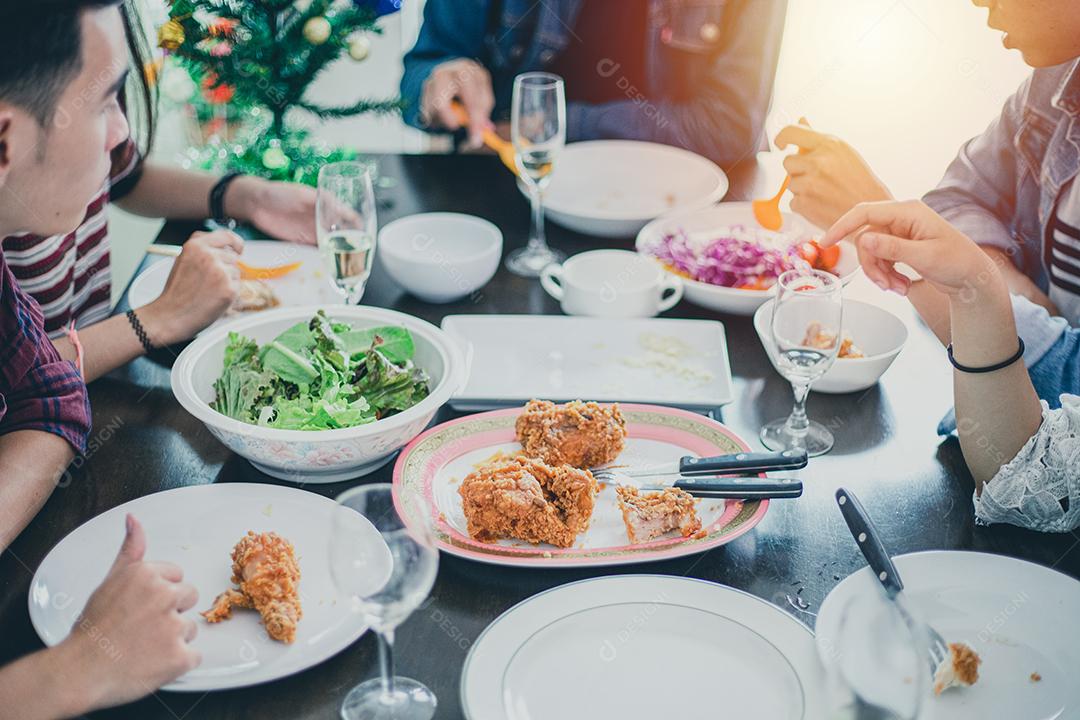 Jantar com o grupo asiático de melhores amigos desfrutando de bebidas à noite enquanto estão sentados à mesa de jantar na cozinha juntos