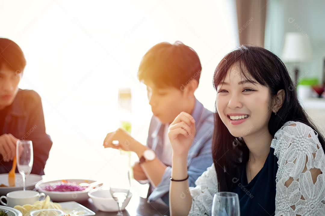 Jantar com o grupo asiático de melhores amigos desfrutando de bebidas à noite enquanto estão sentados à mesa de jantar na cozinha juntos