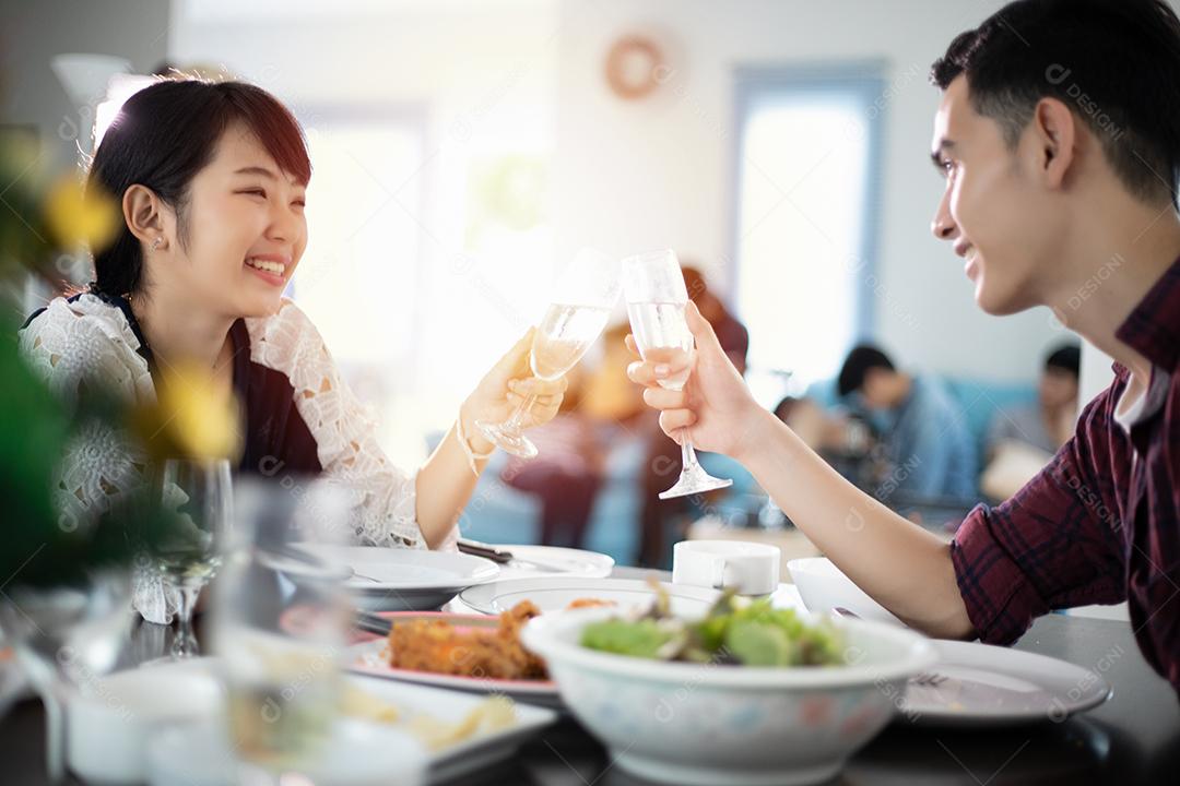Casal jovem asiático desfrutando de um jantar romântico bebidas à noite enquanto está sentado à mesa de jantar na cozinha juntos