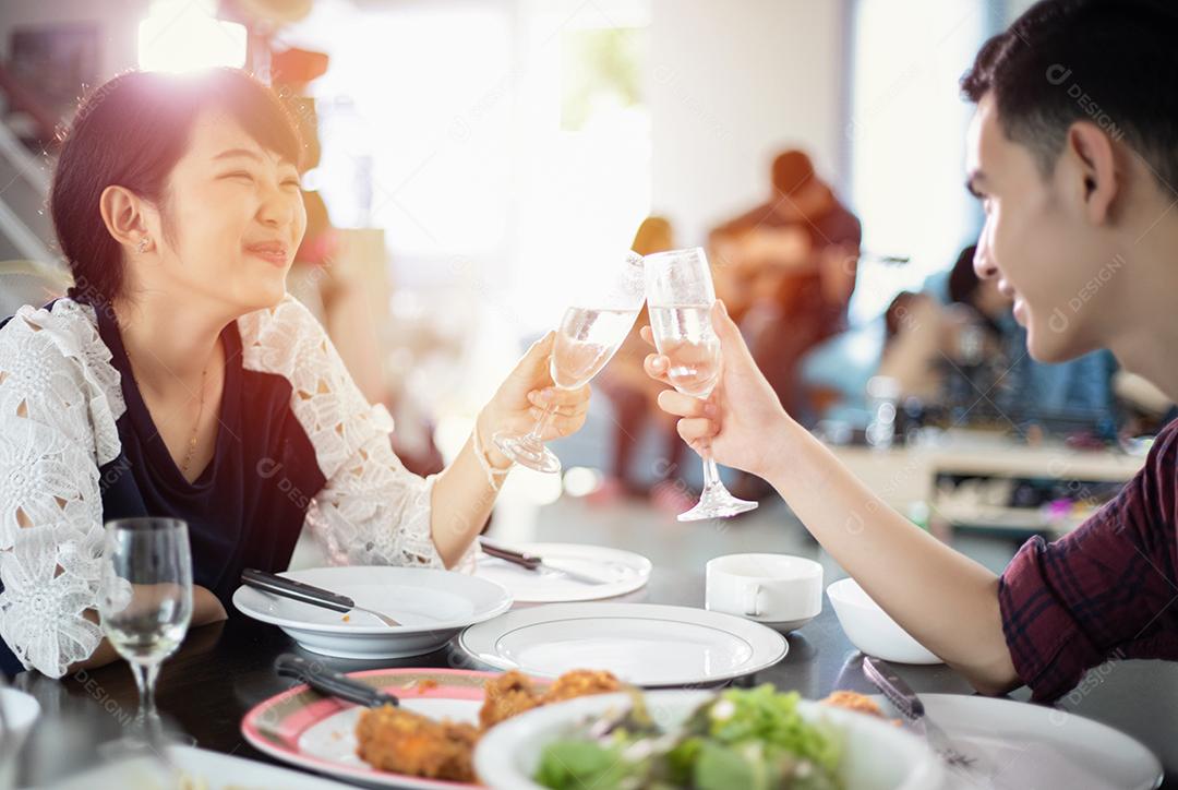 Casal jovem asiático desfrutando de um jantar romântico bebidas à noite enquanto está sentado à mesa de jantar na cozinha juntos