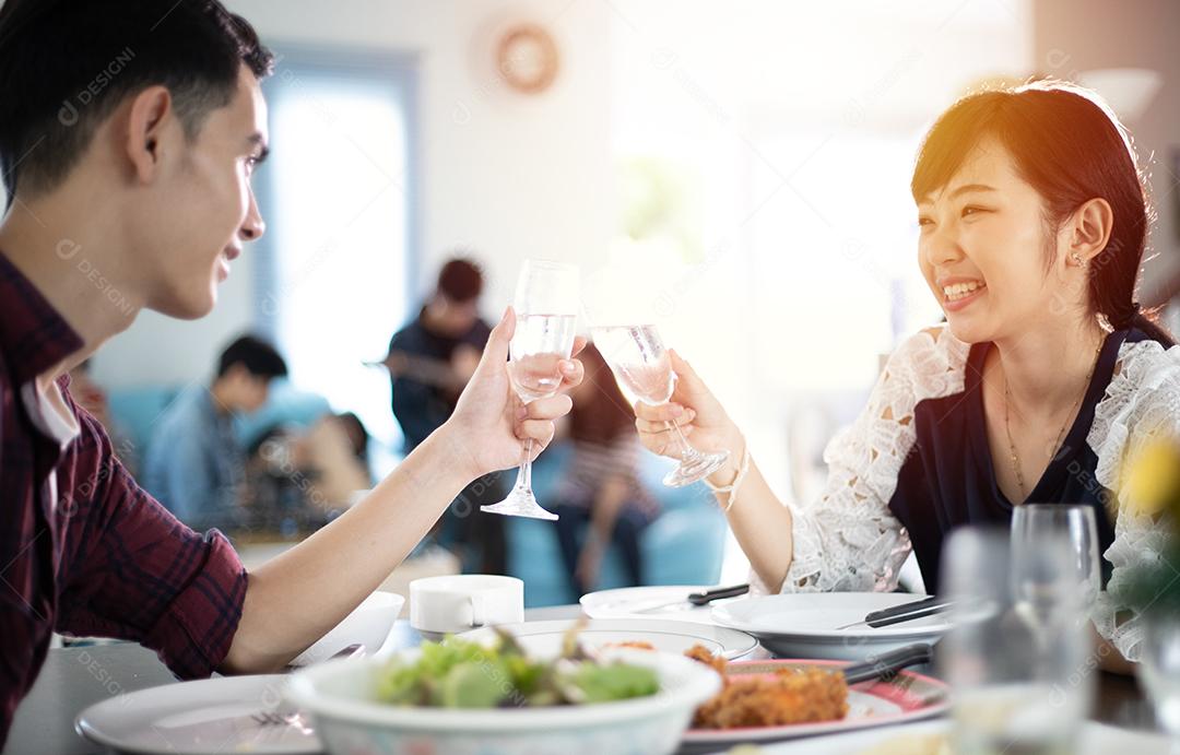 Casal jovem asiático desfrutando de um jantar romântico bebidas à noite enquanto está sentado à mesa de jantar na cozinha juntos