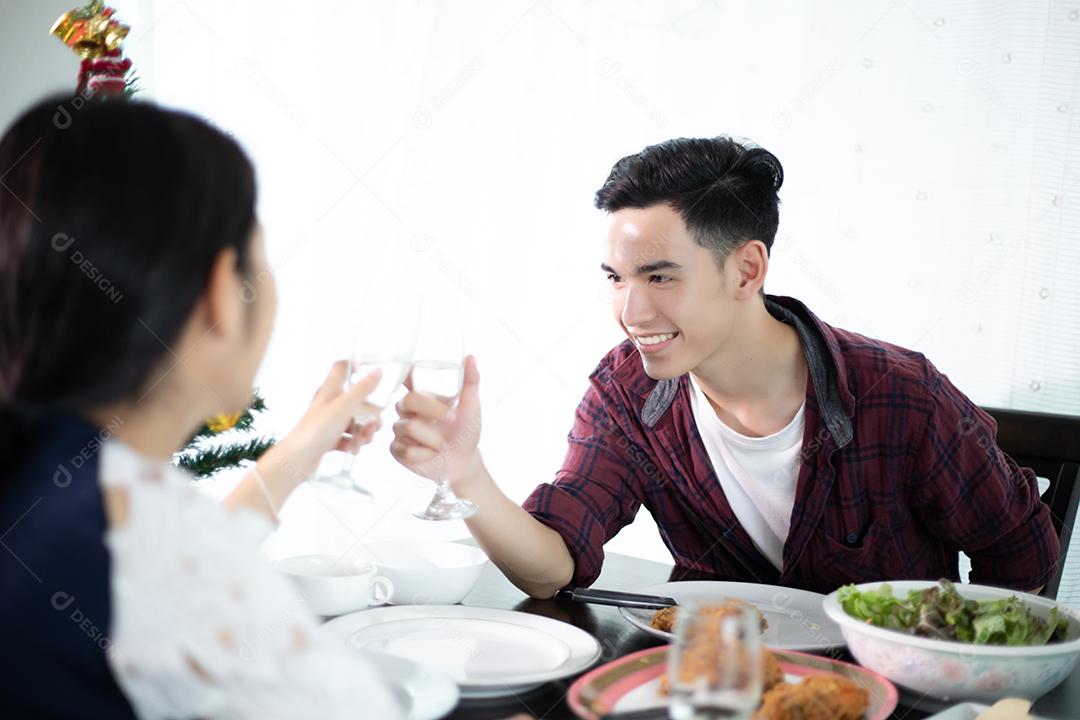 Casal jovem asiático desfrutando de um jantar romântico bebidas à noite enquanto está sentado à mesa de jantar na cozinha juntos