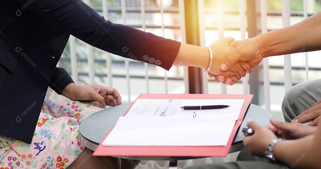 Empresários apertando as mãos e sorrindo seu acordo para assinar contrato e terminar uma reunião