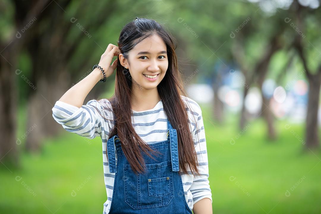 Linda garota asiática sorridente na árvore no parque no verão para relaxar