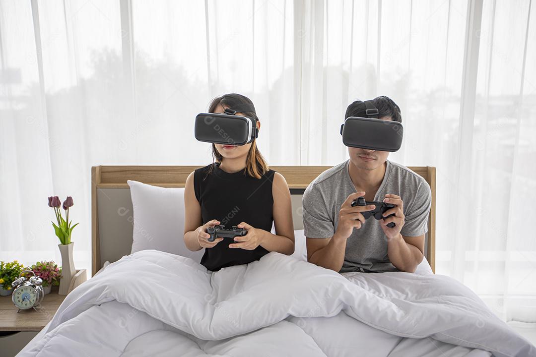 Amante de casal asiático gostando de jogar videogame no quarto de cama, amante de casal asiático se sentindo feliz, divertido e realidade virtual, VR jogando juntos enquanto estava deitado no quarto de cama em casa conceito.