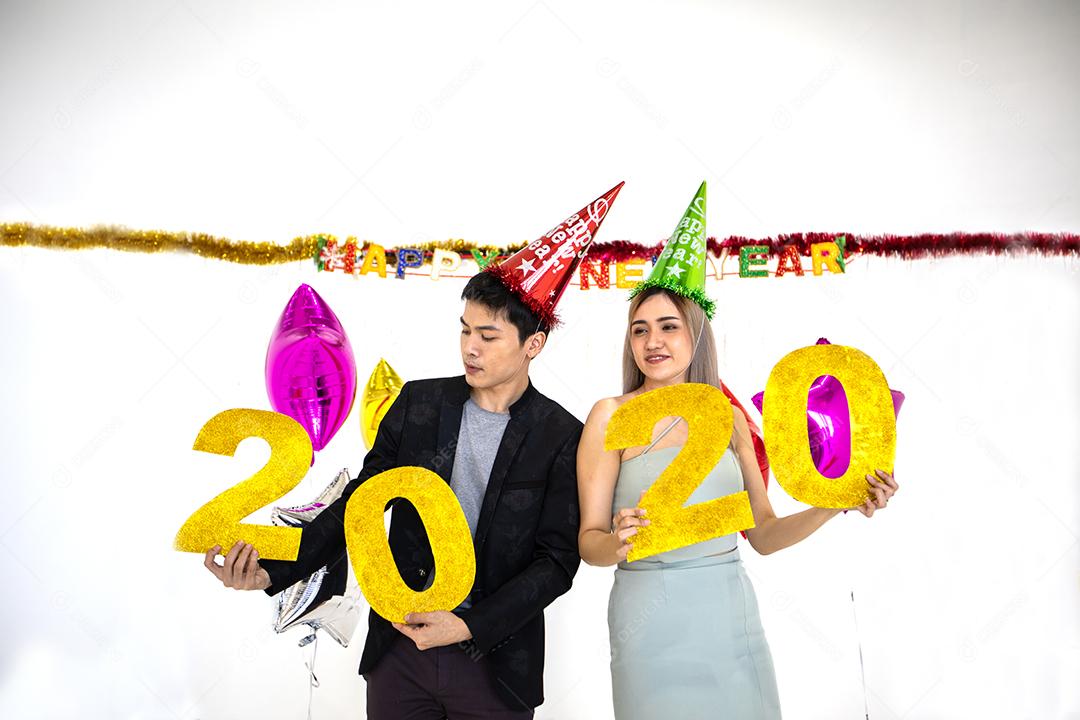 Amante de casal asiático segurando números de 2020 comemorando um ano novo em um bar gritando e rindo e contando até a meia-noite em uma festa de ano novo