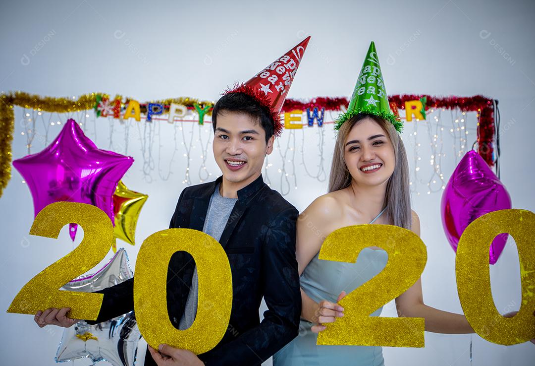 Amante de casal asiático segurando números de 2020 comemorando um ano novo em um bar gritando e rindo e contando até a meia-noite em uma festa de ano novo