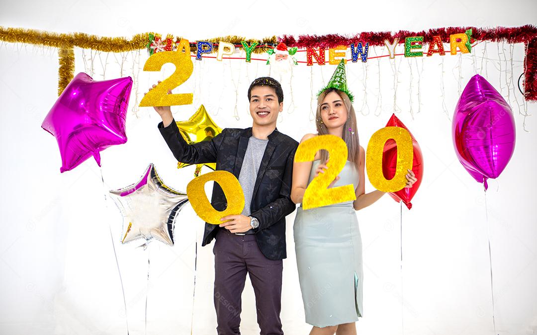 Amante de casal asiático segurando números de 2020 comemorando um ano novo em um bar gritando e rindo e contando até a meia-noite em uma festa de ano novo