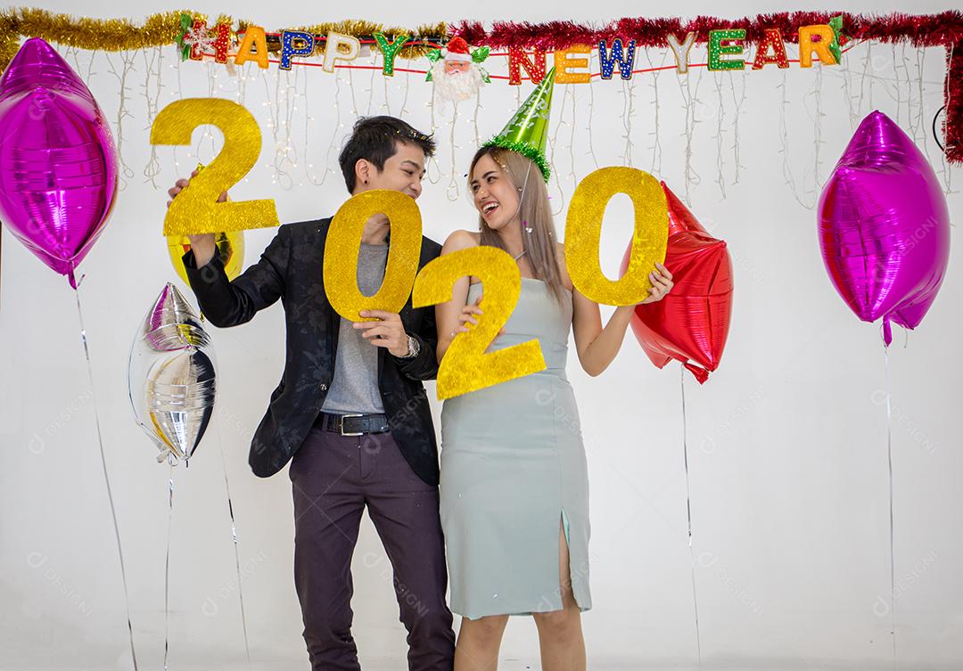 Amante de casal asiático segurando números de 2020 comemorando um ano novo em um bar gritando e rindo e contando até a meia-noite em uma festa de ano novo