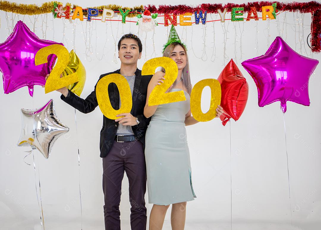 Amante de casal asiático segurando números de 2020 comemorando um ano novo em um bar gritando e rindo e contando até a meia-noite em uma festa de ano novo