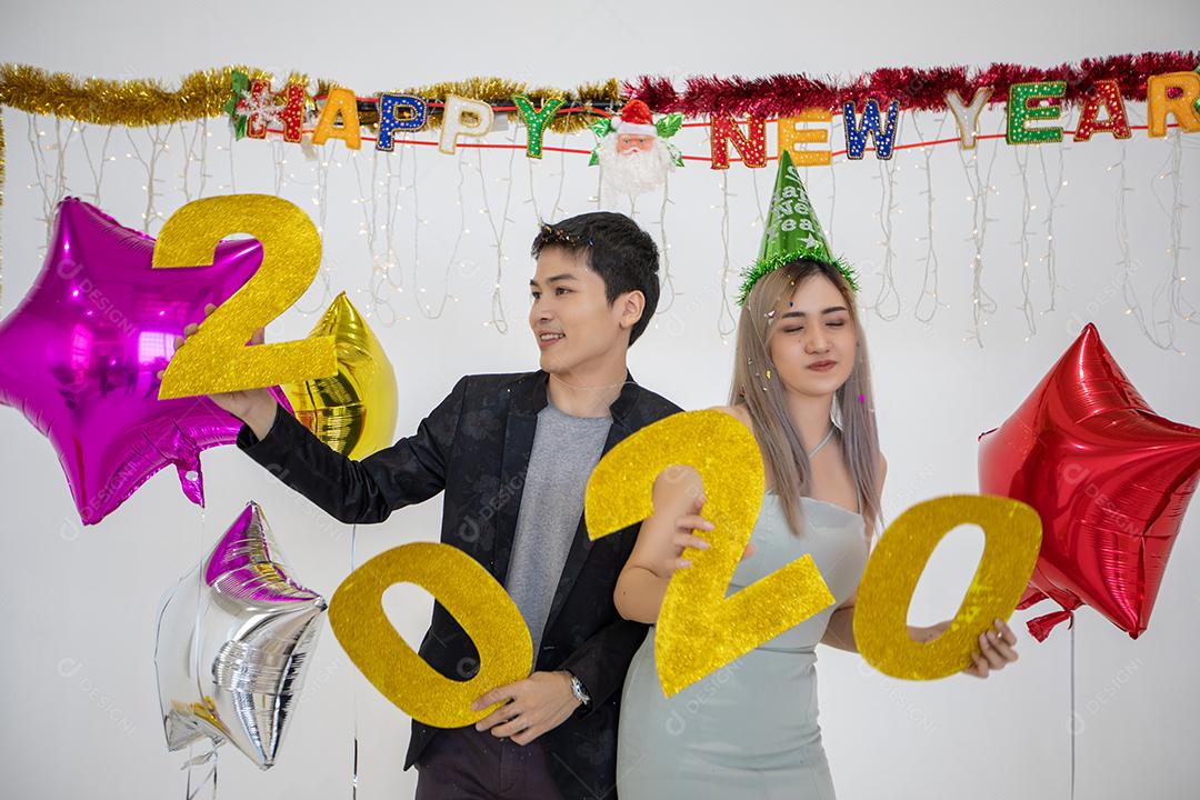 Amante de casal asiático segurando números de 2020 comemorando um ano novo em um bar gritando e rindo e contando até a meia-noite em uma festa de ano novo