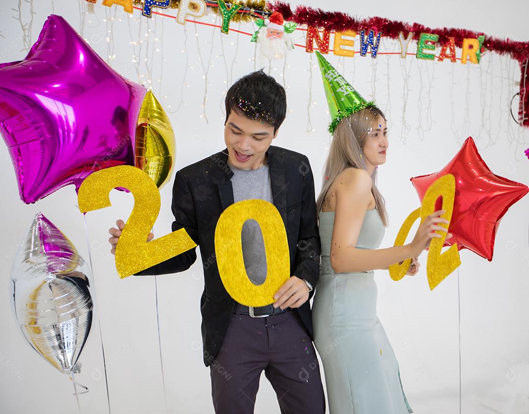 Amante de casal asiático segurando números de 2020 comemorando um ano novo em um bar gritando e rindo e contando até a meia-noite em uma festa de ano novo