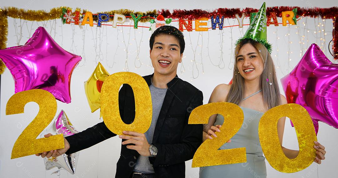 Amante de casal asiático segurando números de 2020 comemorando um ano novo em um bar gritando e rindo e contando até a meia-noite em uma festa de ano novo