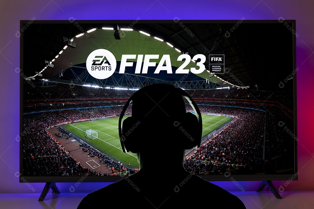 Homem com fone de ouvido joga FIFA 23 na tela da TV São Paulo, Brasil.