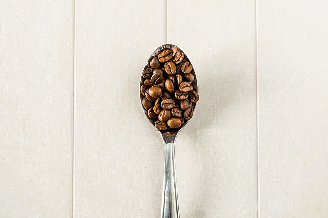 grãos de café na colher metálica, fundo branco