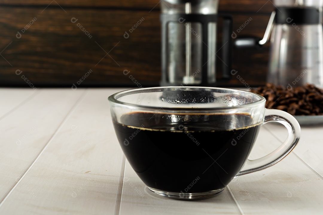 café preto no copo de vidro transparente com elementos no fundo