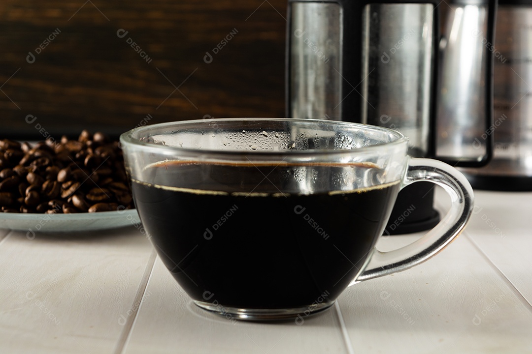 café preto no copo de vidro transparente com elementos no fundo