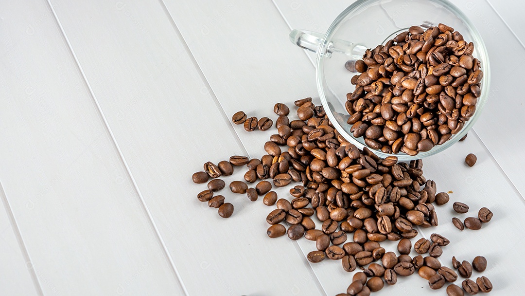 grãos de café em copo de vidro caindo na mesa