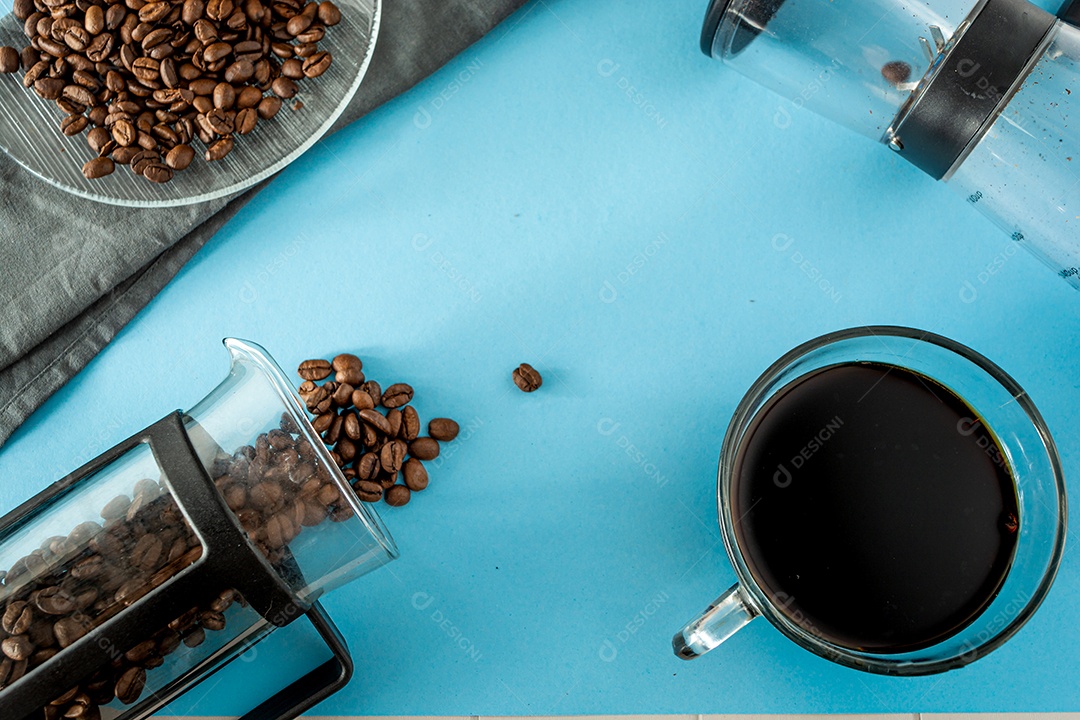 fundo de café preto com grãos e elementos sobre mesa azul, imprensa francesa, pano cinza