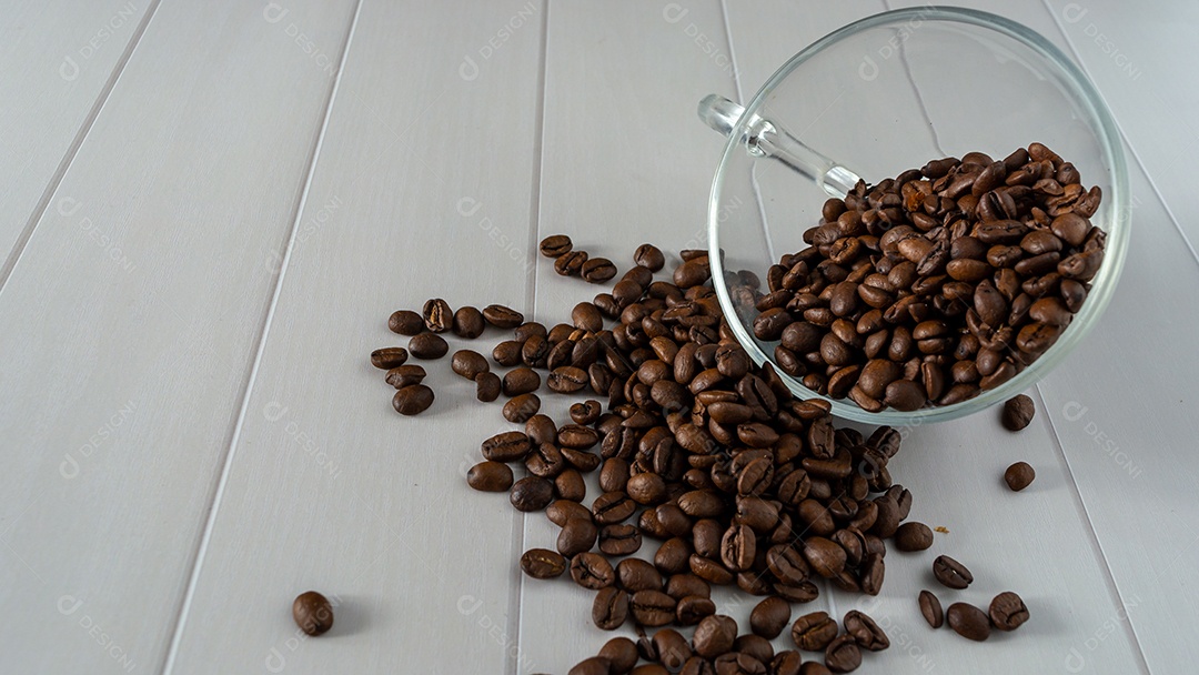 pilha de grãos de café caindo do copo de vidro sobre fundo branco