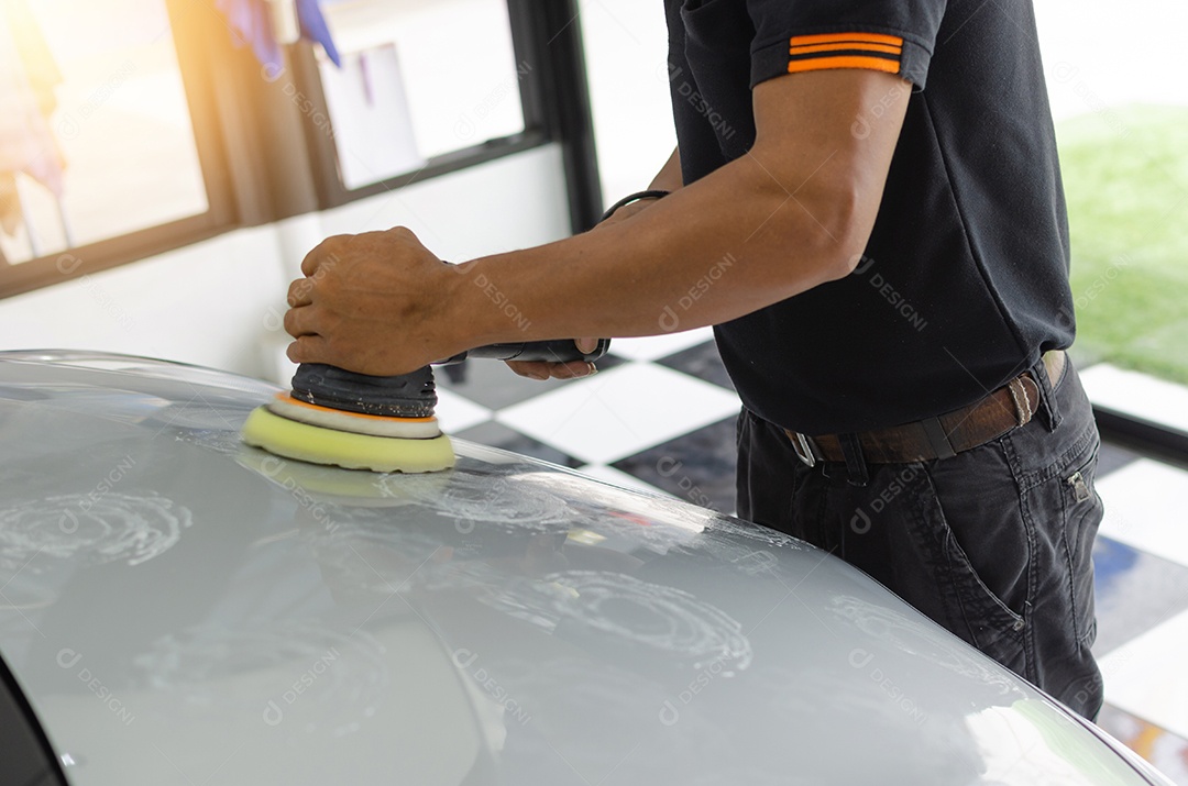 As mãos de um homem segurando a ferramenta de trabalho polindo o carro.