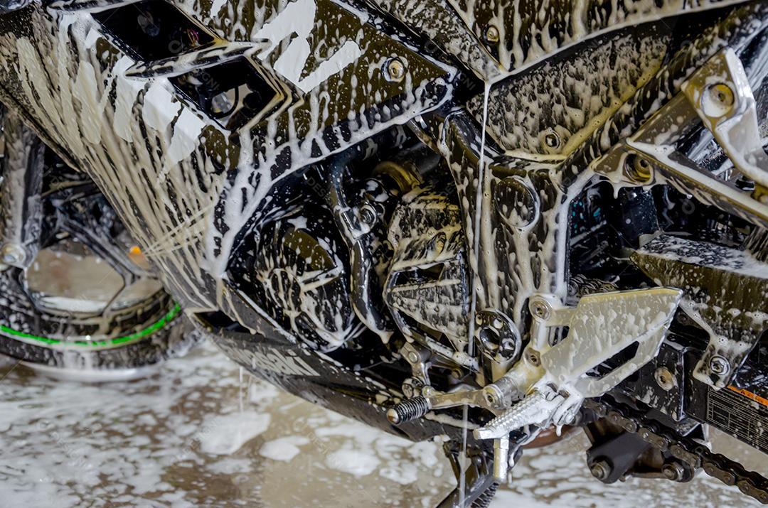 Lavando a motocicleta com sabão com espumas