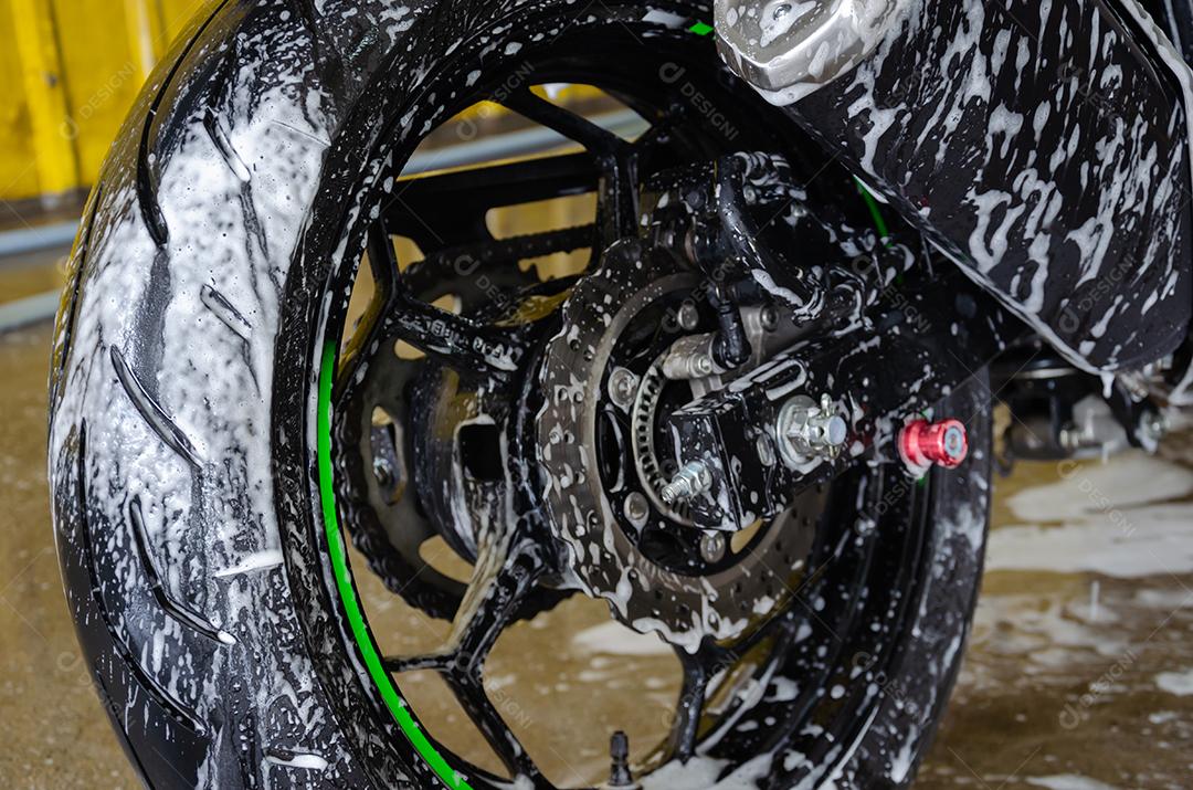 Lavando a motocicleta com sabão com espumas