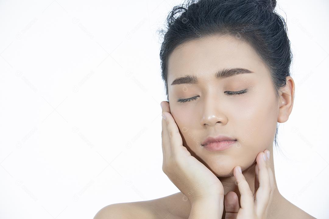 Uma linda mulher asiática usando um produto de cuidados com a pele, hidratante ou loção cuidando de sua pele seca. Creme hidratante nas mãos femininas.