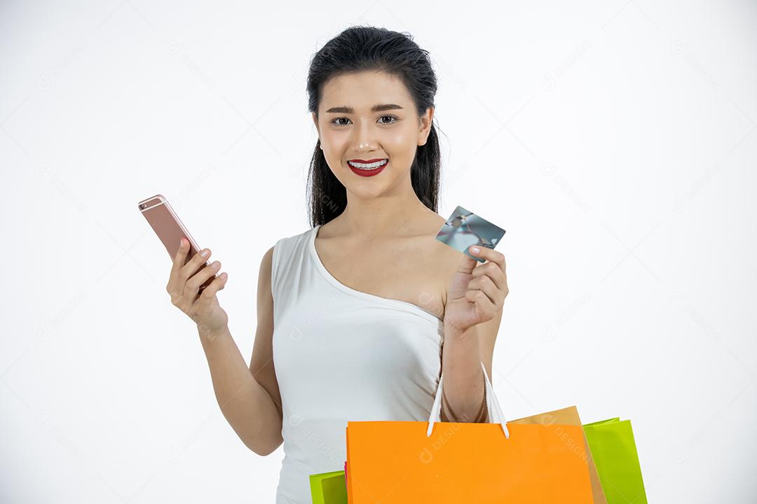 Mulheres asiáticas e linda garota estão segurando sacolas de compras e usando um telefone inteligente e sorrindo enquanto fazem compras on-line com cartão de crédito