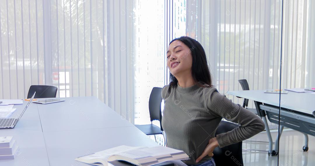 Mulher asiática esticando depois de ler o livro e trabalhar duro e sorrindo na biblioteca