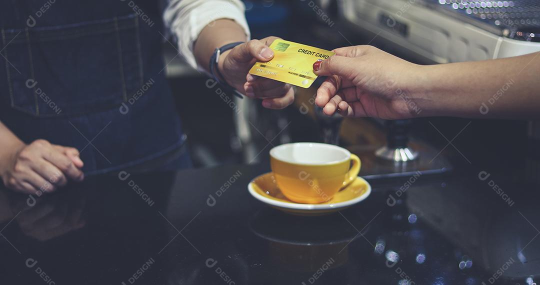 Barista atendendo cliente e mulher está pagando café com cartão de crédito na cafeteria