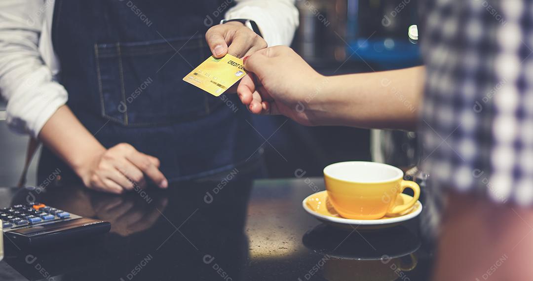 Barista atendendo cliente e mulher está pagando café com cartão de crédito na cafeteria