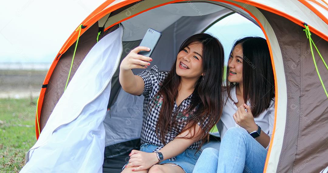 Um grupo de amigos asiáticos jogando Ukelele e passando o tempo fazendo um piquenique nas férias de verão. Eles estão felizes e se divertem nos feriados.