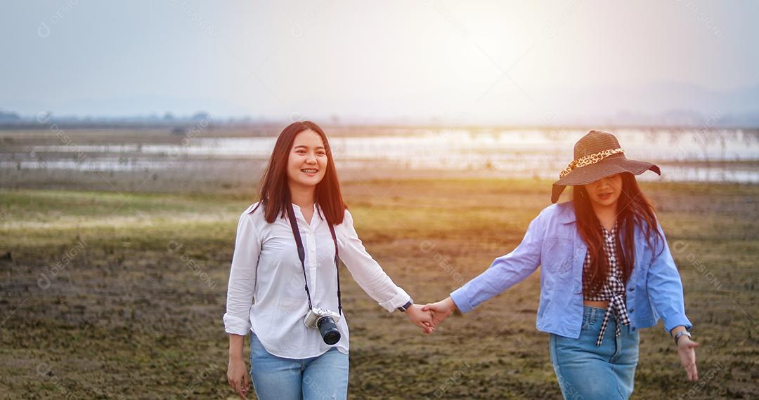 Mulheres jovens asiáticas estão se divertindo e rindo e abraçando no campo verde à noite.