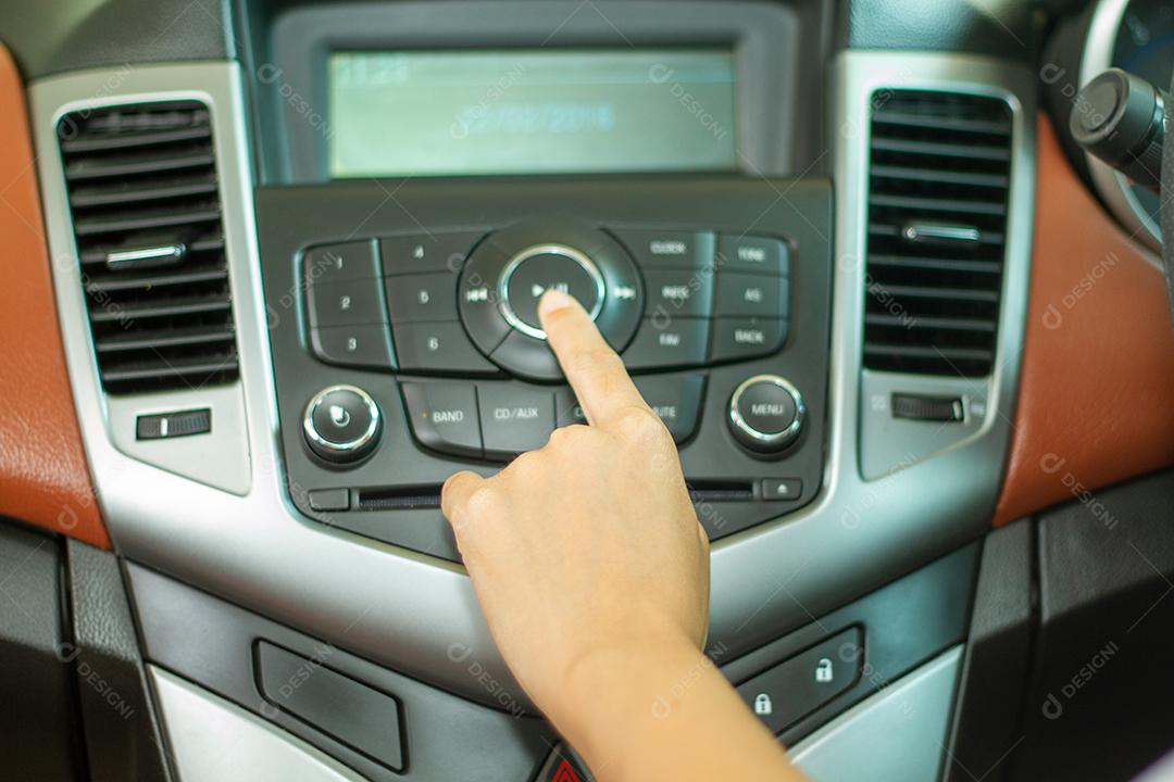 As mulheres asiáticas pressionam o botão no rádio do carro para ouvir música.