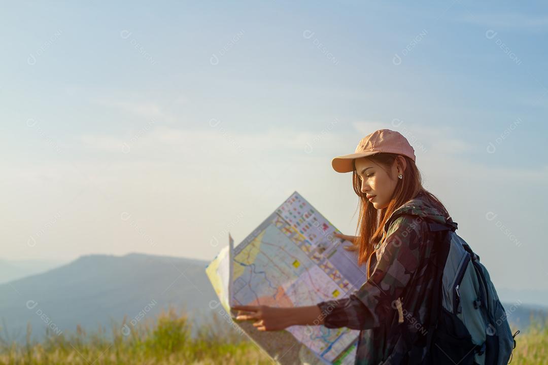 mulheres asiáticas com mochila brilhante olhando para um mapa. Vista de trás do viajante turístico na montanha de fundo, mãos femininas usando smartphone, segurando gadget
