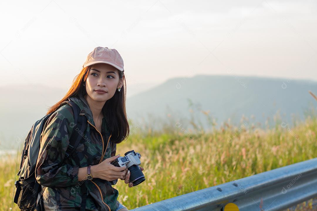 mulheres asiáticas com mochila tirando uma foto à vista no pico da montanha à beira-mar ao nascer do sol