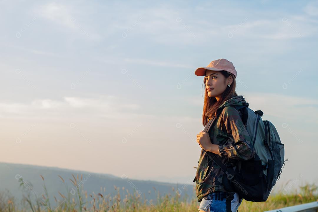 Mulher asiática de retrato mochila. Ela estava sorrindo e feliz em viajar no pico da montanha à beira-mar ao nascer do sol