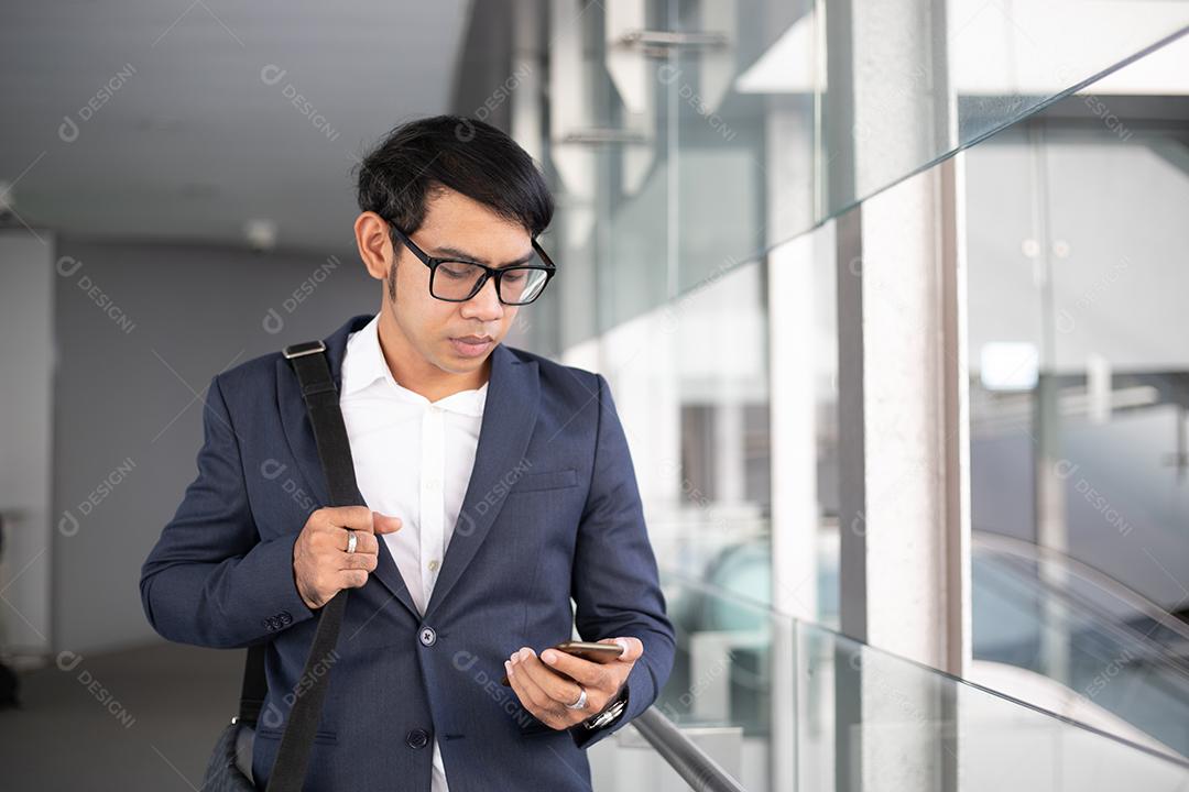Empresários asiáticos usando máscara e usando seus telefones e vão trabalhar de manhã.