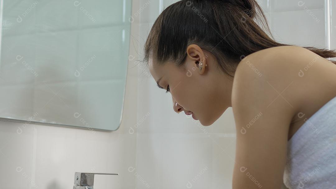 Jovem mulher lavando o rosto no banheiro em casa