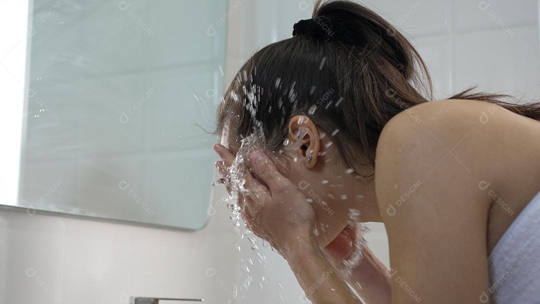 Jovem mulher lavando o rosto no banheiro em casa