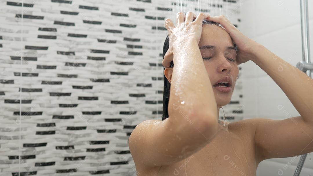 Jovem tomando banho e lavando o cabelo no banheiro