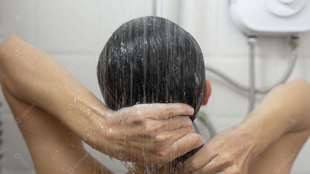 Jovem tomando banho e lavando o cabelo no banheiro
